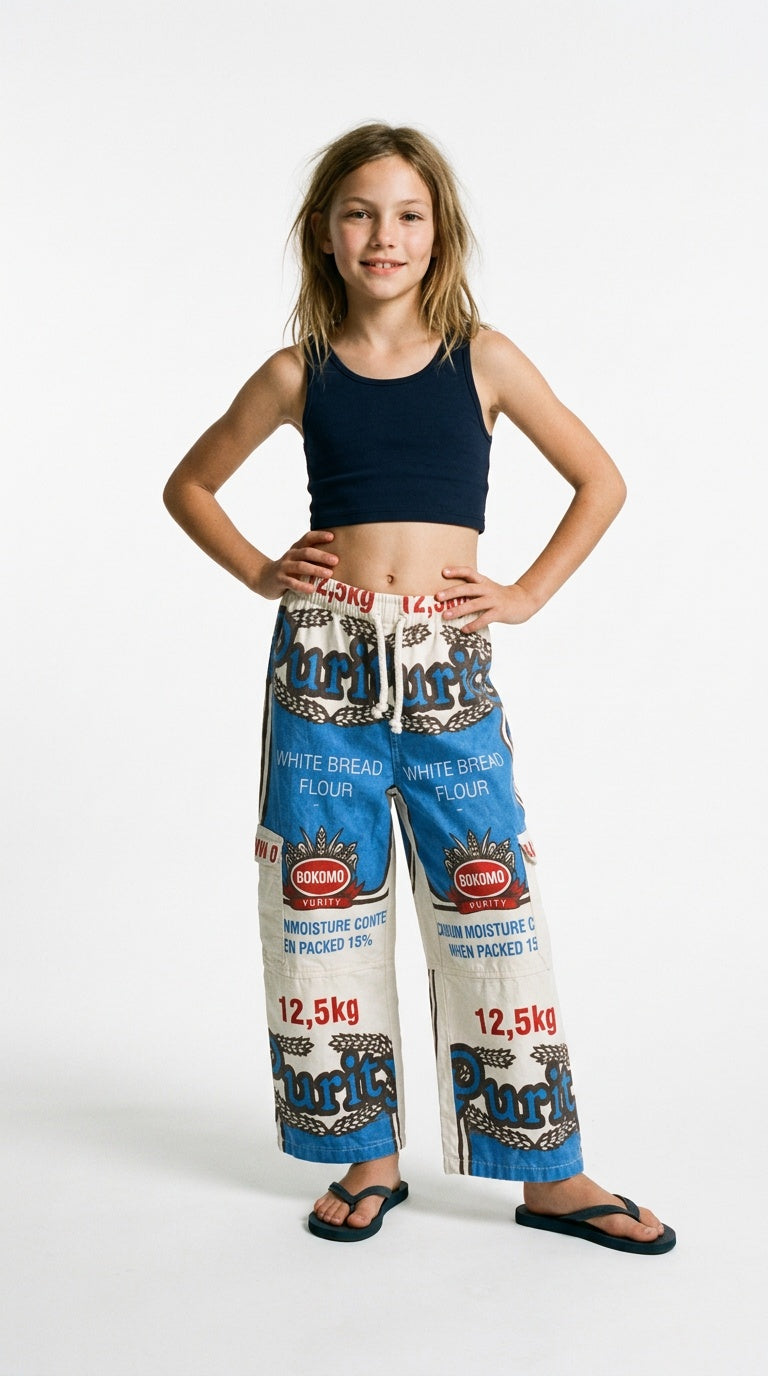 Girl in a navy crop top and flip-flops wearing wide-leg Purity white bread flour bag pants, hands on hips